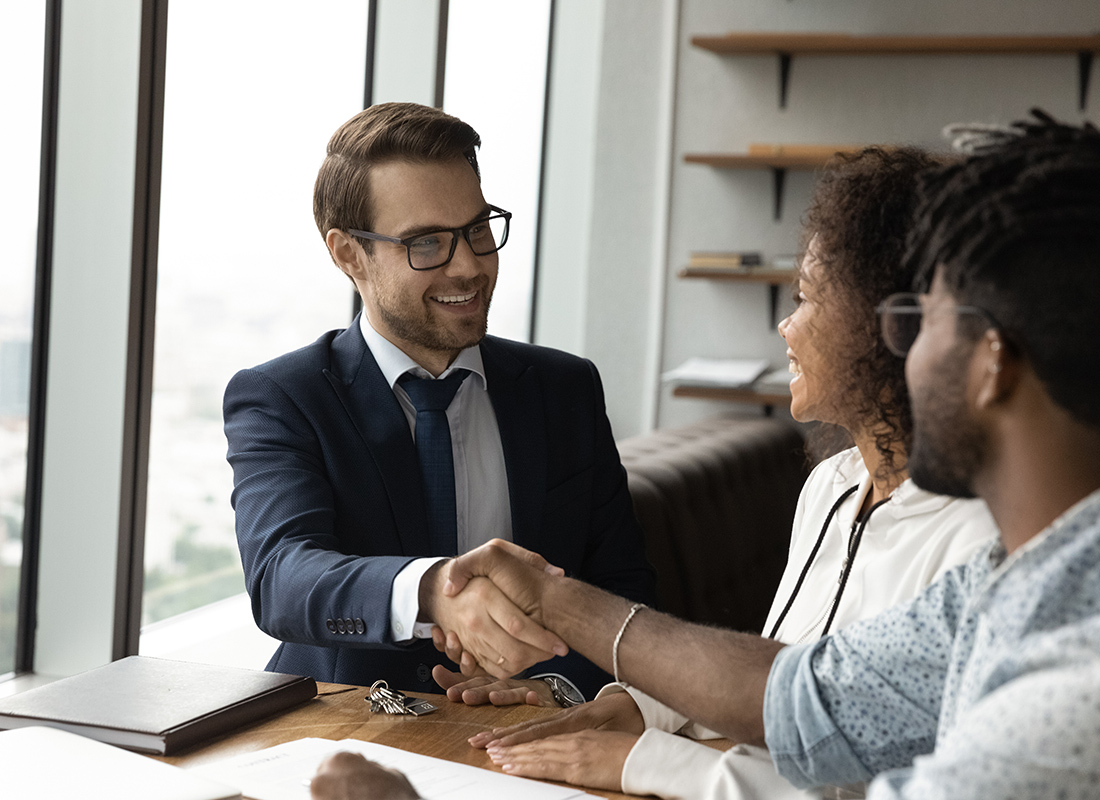 Contact - Friendly Agent Shaking Hands With a Couple in His Office