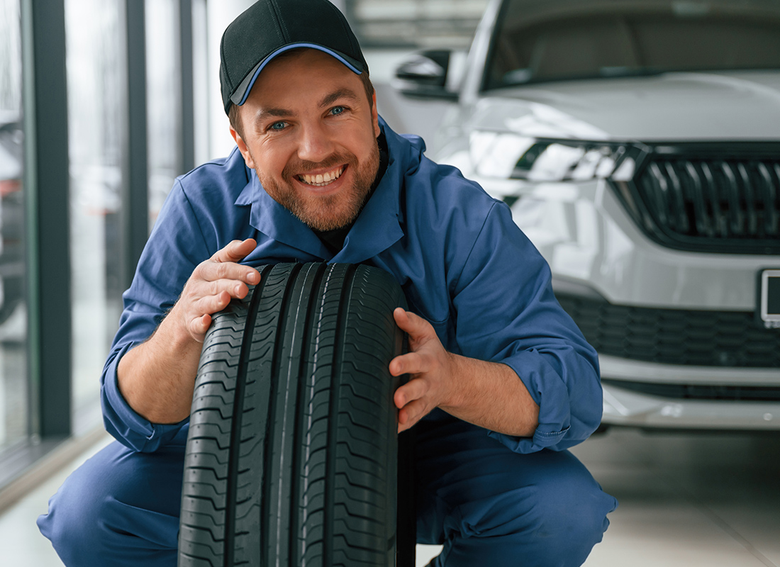 Insurance by Industry - Friendly Auto Mechanic Holding a Tire